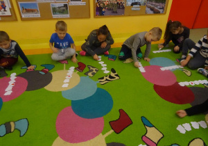 Szóstka dzieci przelicza szablony mapy Polski ułożone w rzędzie, odwracają trzeci z kolej.